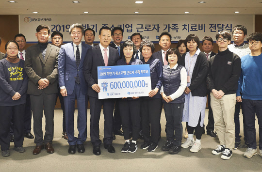 김도진 은행장(앞줄 왼쪽 네 번째)과 중소기업 근로자 가족들이 9일 을지로 기업은행 본점에서 치료비 전달식을 마치고 기념촬영을 하고 있다.(사진=기업은행)